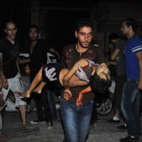 Un homme porte un enfant blessé à Alep